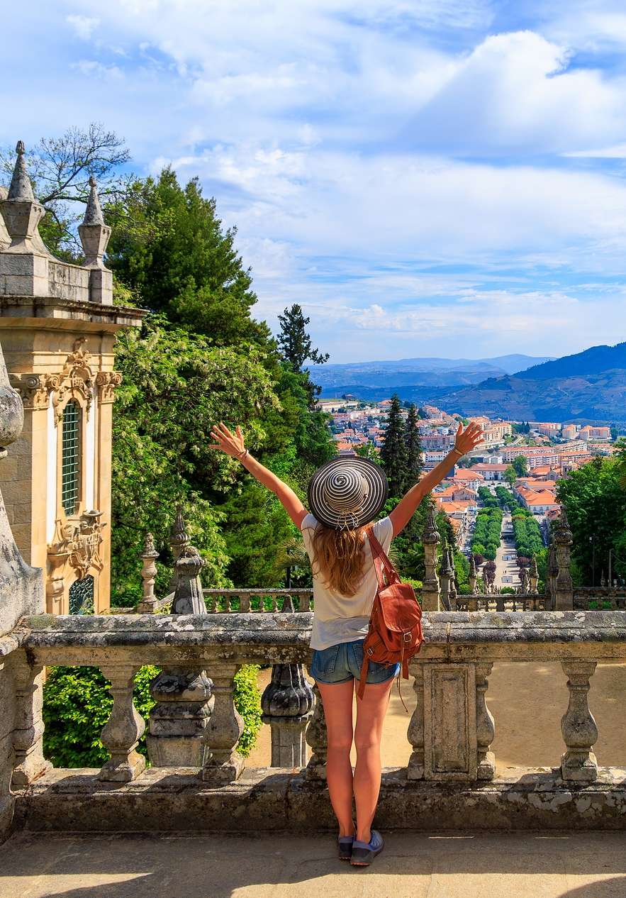 Persona con brazos abiertos disfrutando la vista de Viseu desde una escalinata histórica