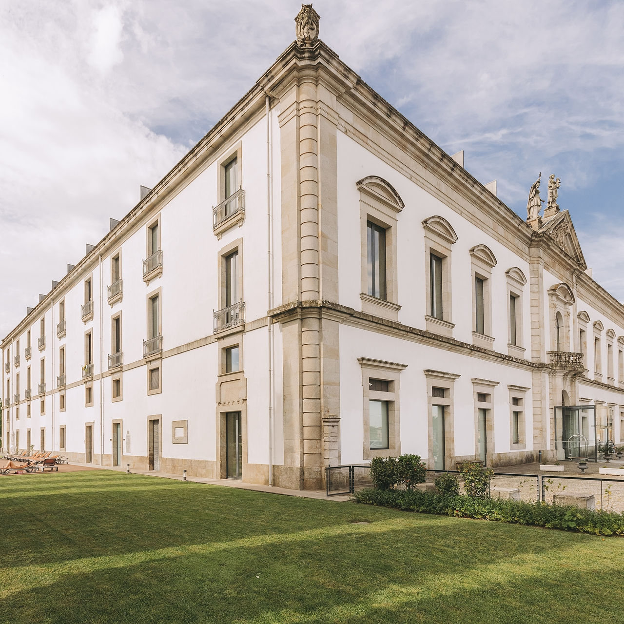 Fachada histórica de Pousada Viseu, con paredes de piedra blanca y césped frente a ella