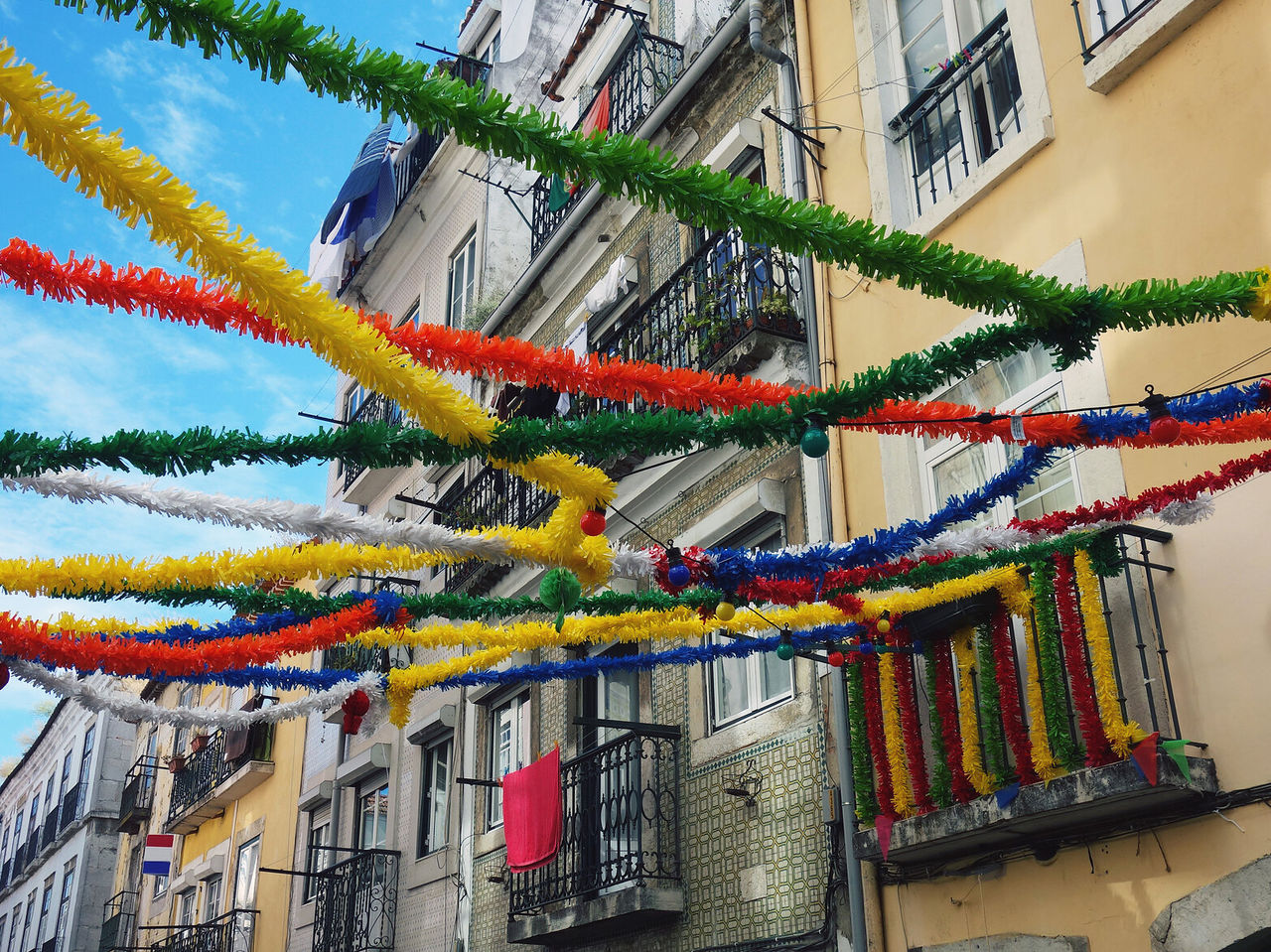 Explora Hoteles en Lisboa con calles adornadas con guirnaldas coloridas entre balcones y fachadas antiguas