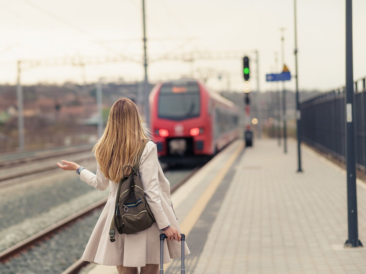 Explorá Hoteles en Lisboa con viajeros esperando junto a un tren rojo en una estación al atardecer