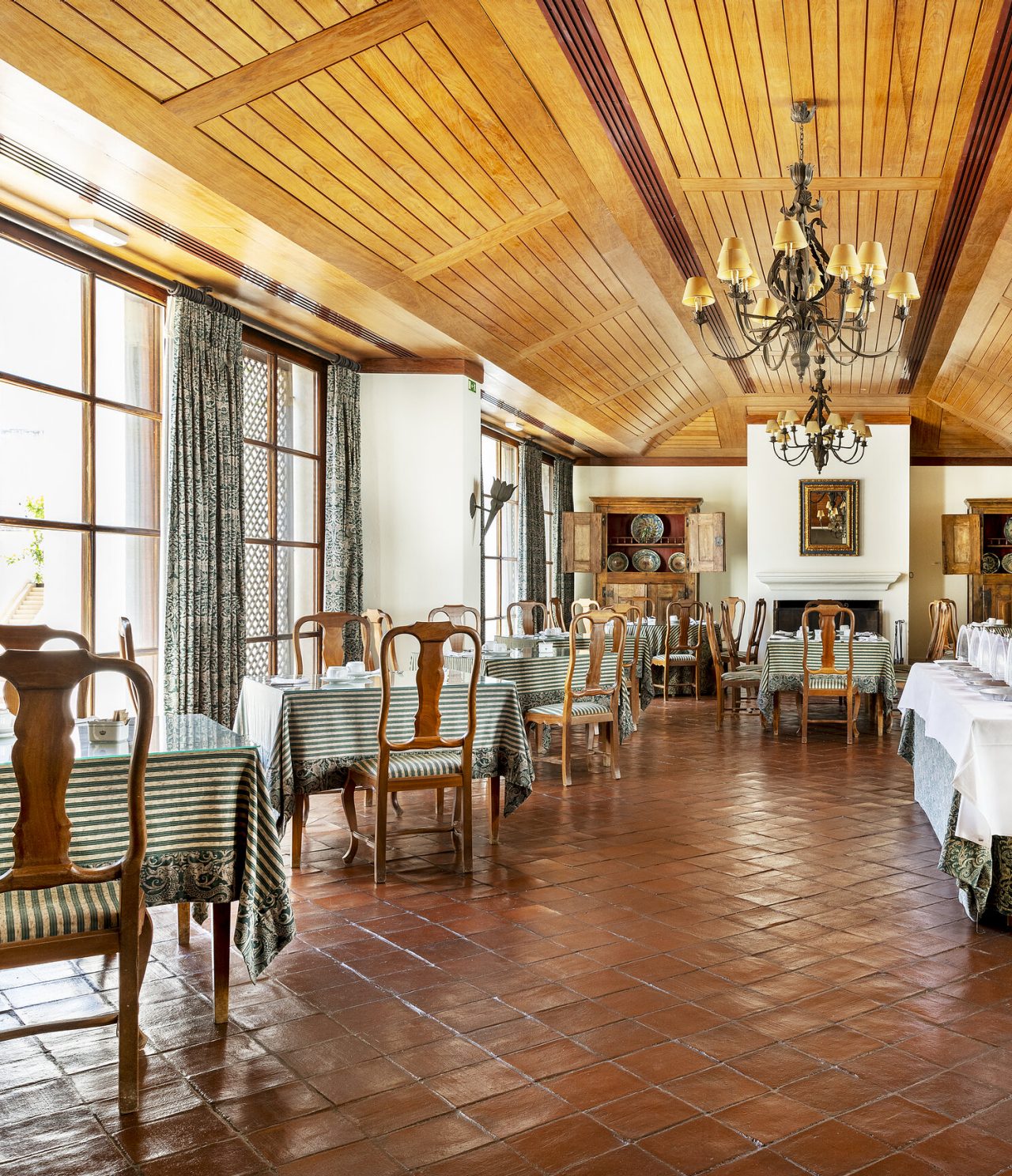 O restaurante D. Carlos, do Hotel Histórico em Vila Viçosa, tem uma sala com mesas, cadeiras e teto de madeira 