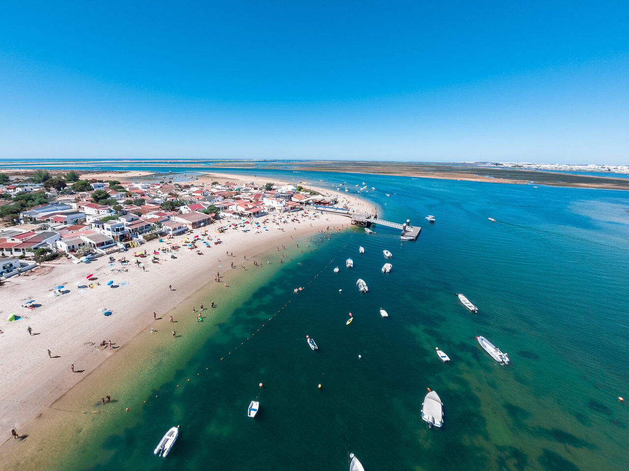 Vista paradisíaca aérea da ilha da Armona, no Algarve, com águas cristalinas, e barcos na Ria Formosa