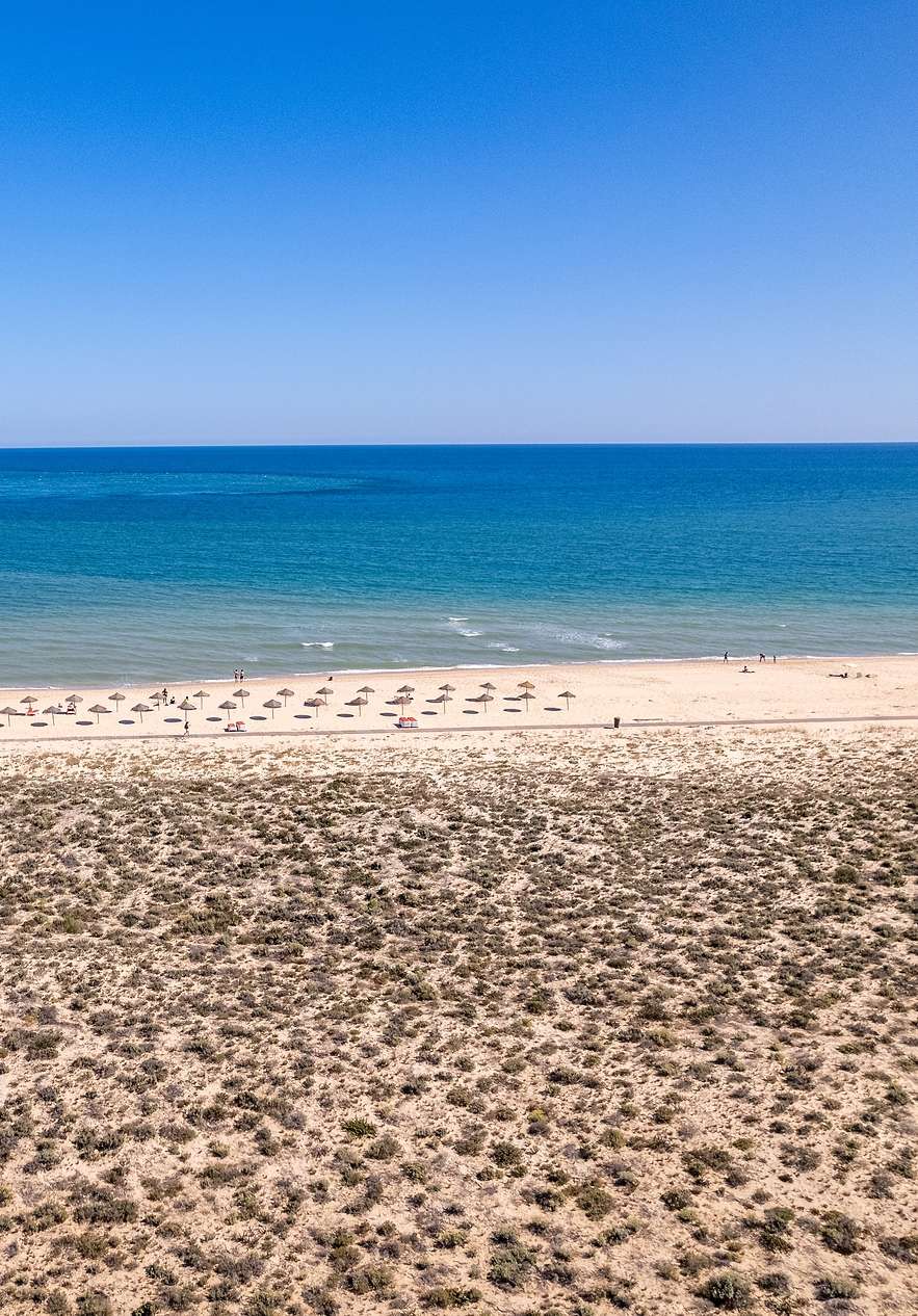 Ilha Deserta em Faro, com a praia extensa e praticamente deserta, com o mar azul e cristalino ao fundo