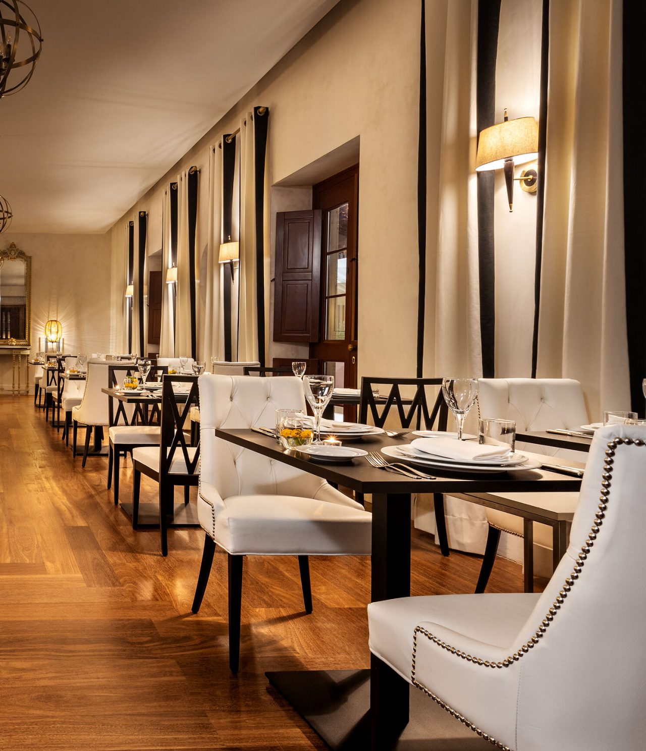O restaurante Visconde, do Hotel Histórico em Faro, tem uma sala ampla, com várias mesas com cadeiras pretas e brancas