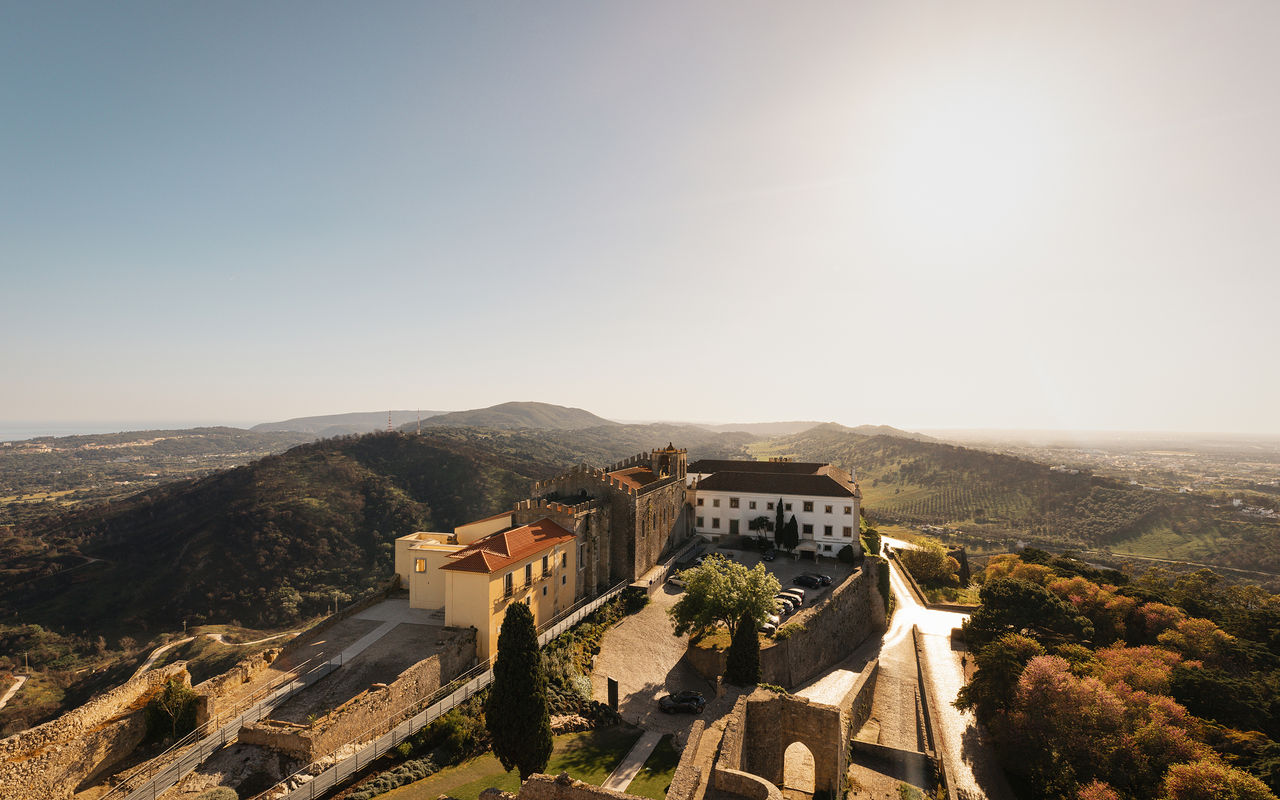 Vista panorâmica da Pousada Castelo Palmela, Hotel com Vista para a Serra da Arrábida, com um castelo com muralhas e torres 