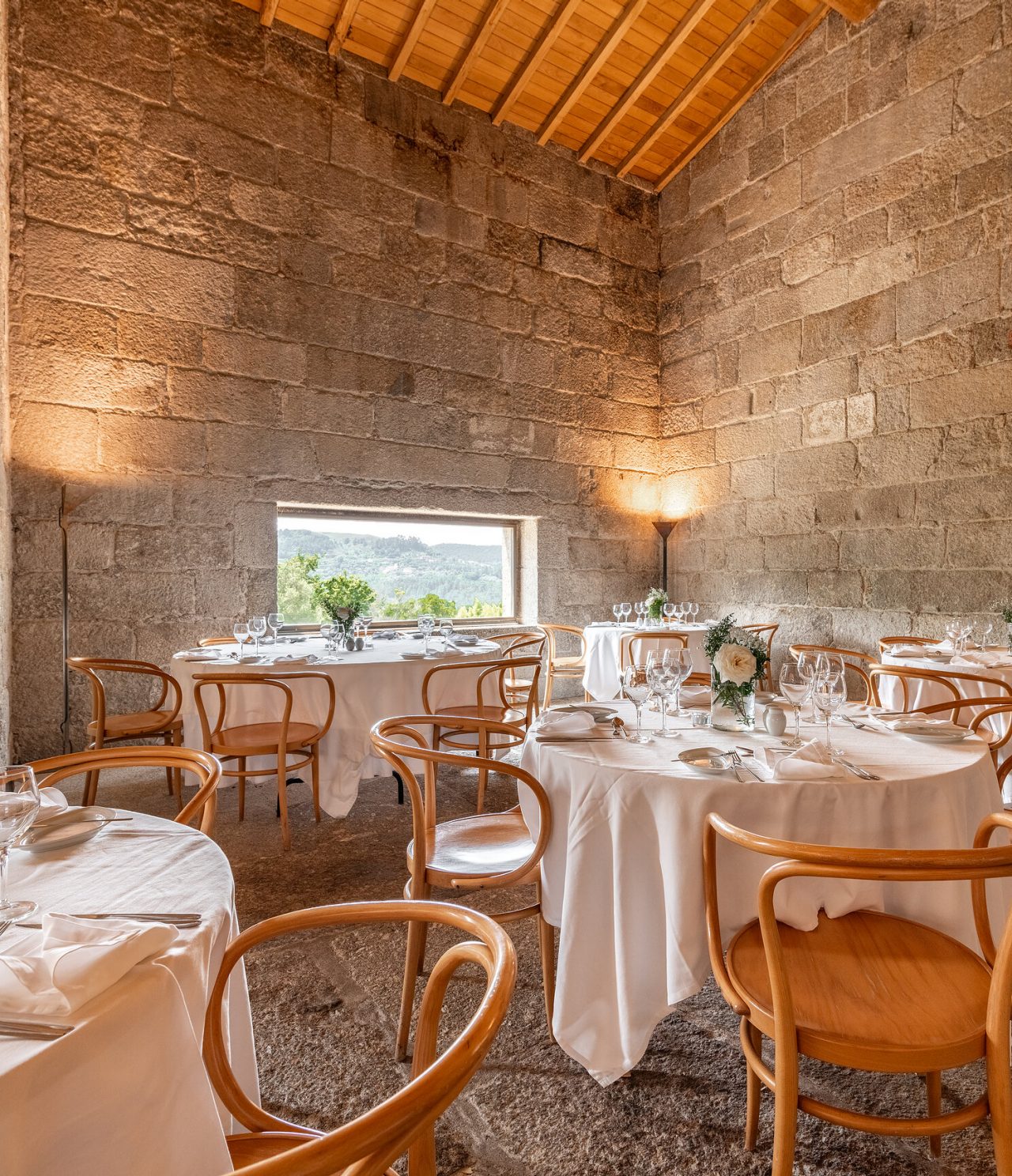 O restaurante da Pousada Mosteiro Amares, do Hotel Histórico no Gerês, tem mesas redondas e paredes de pedra