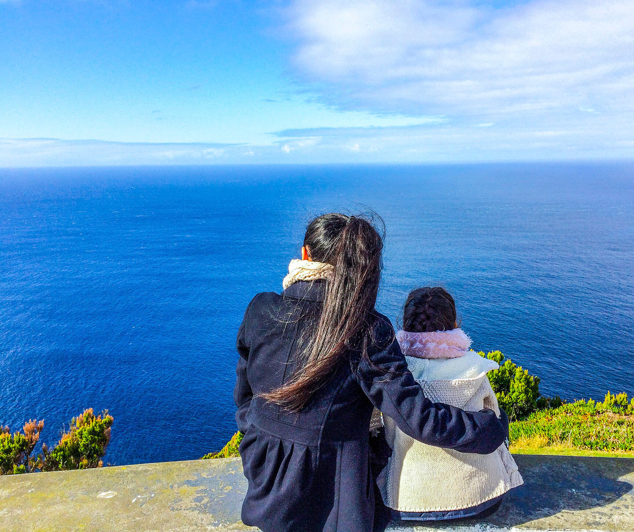 Hotel Açores com vista para duas pessoas abraçadas observando o oceano azul em um mirante costeiro