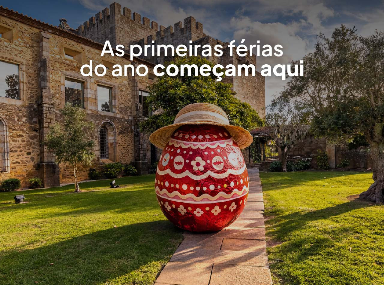 Grande ovo de Páscoa decorado com chapéu em jardim gramado diante de construção histórica de pedra