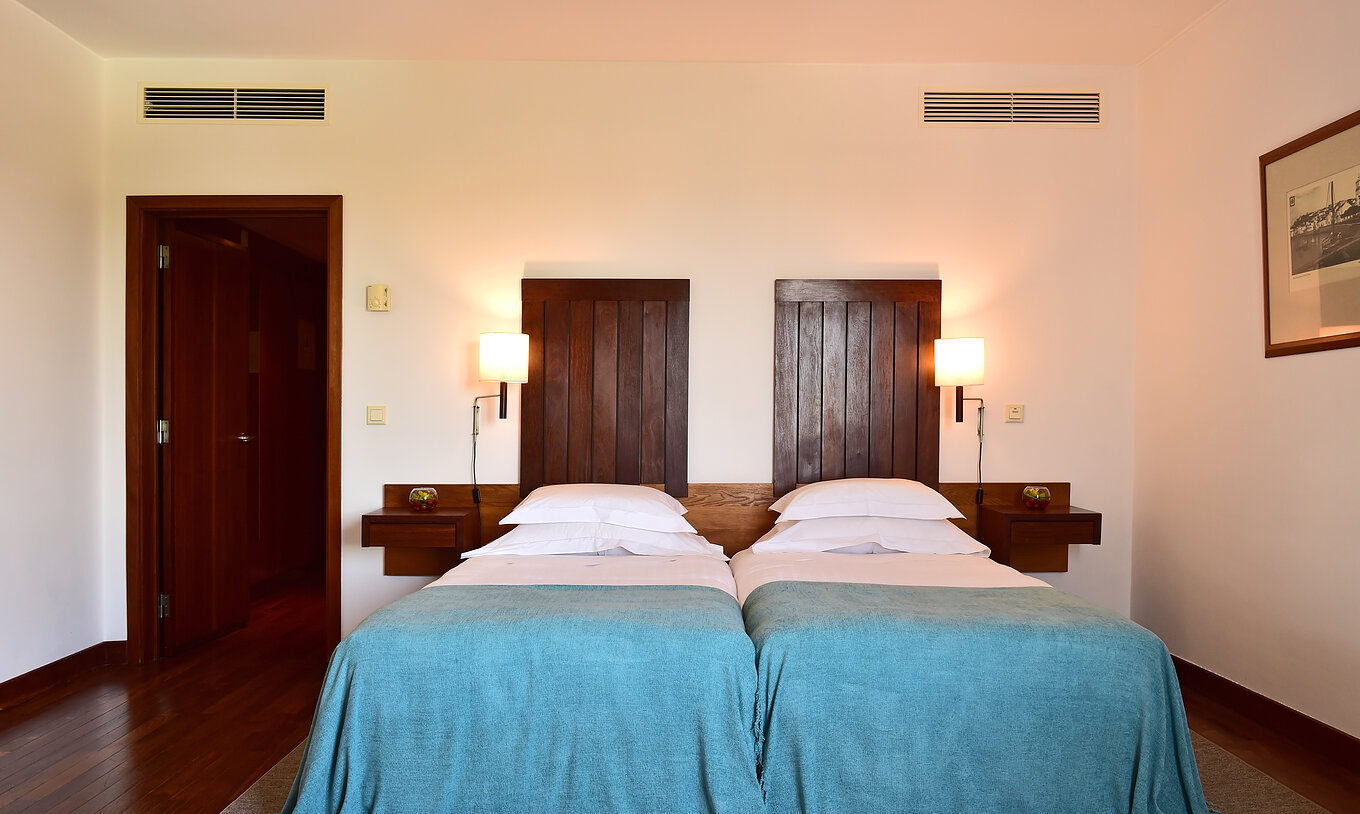 Das Klassische Zimmer der Pousada Castelo Alcácer do Sal hat zwei getrennte Betten, mit blauer Bettdecke und Holz Kopfteil