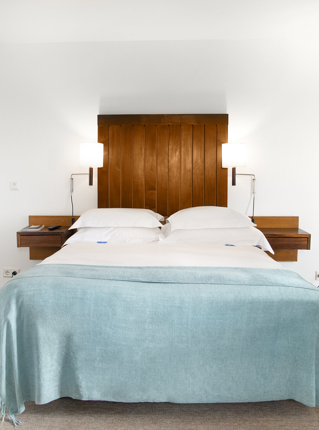 Die Junior Suite der Pousada Castelo Alcácer do Sal hat ein Doppelbett mit einer blauen Decke und Holz Kopfteil