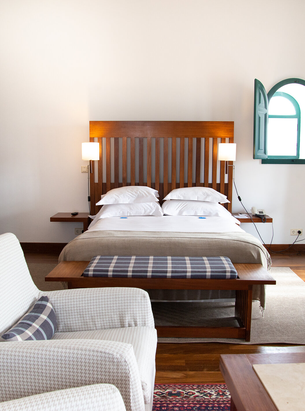 Die Spezial Suite der Pousada Castelo Alcácer do Sal hat ein Doppelbett mit einer beige Decke und einem Sessel