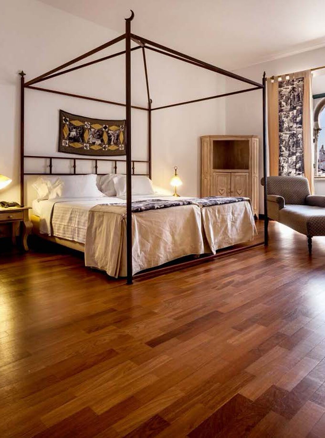 Die Standard Suite der Pousada Castelo Alvito hat zwei Betten einen Sessel und ein Fenster mit Bögen und Blick auf das Dorf