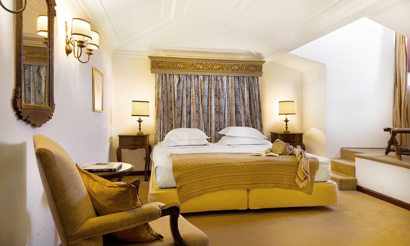 Das Klassikzimmer hat ein Doppelbett, einen Sessel und zwei Nachttische in der Pousada Castelo Estremoz