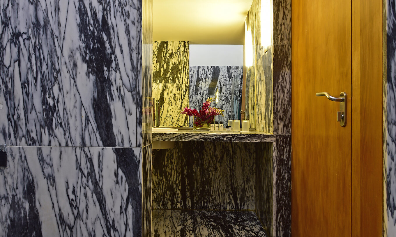 Das Superior Zimmer der Pousada Convento Arraiolos hat ein Bad aus Marmor mit Waschbecken und Blumenvase