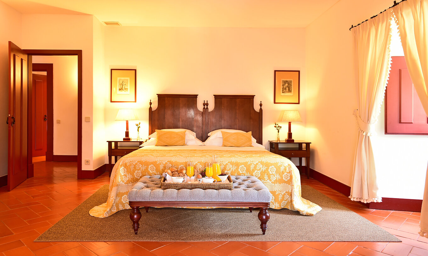 Die Spezial Suite der Pousada Convento Beja hat ein Doppelbett mit gelber Bettdecke und ein Tablett mit Frühstück