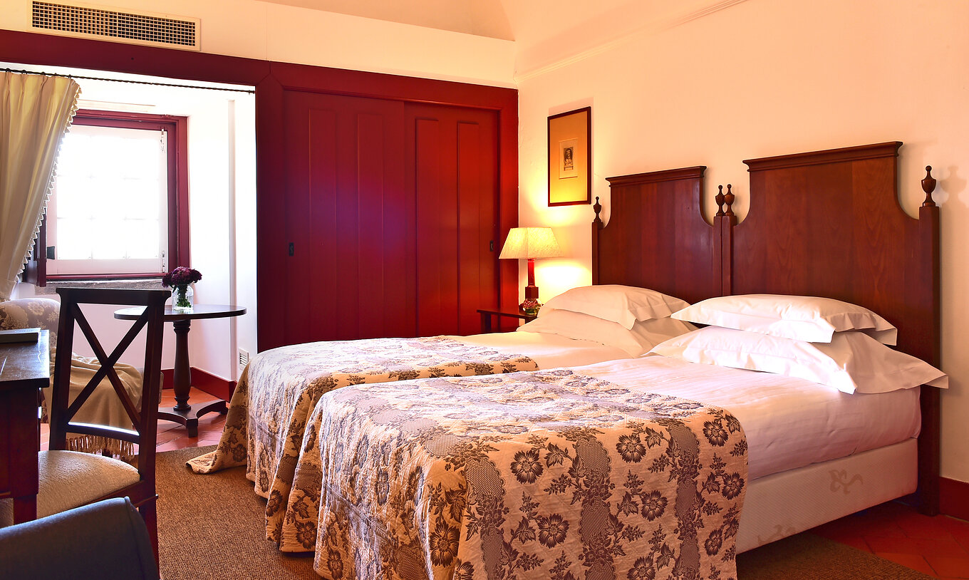 Das Superior Zimmer der Pousada Convento Beja hat zwei Betten mit grauer Bettdecke ein Fenster und Schränke