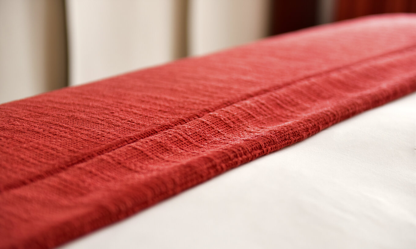 Das Superior Doppelzimmer der Pousada Marvão hat eine rote Decke am Fußende des Bettes gefaltet