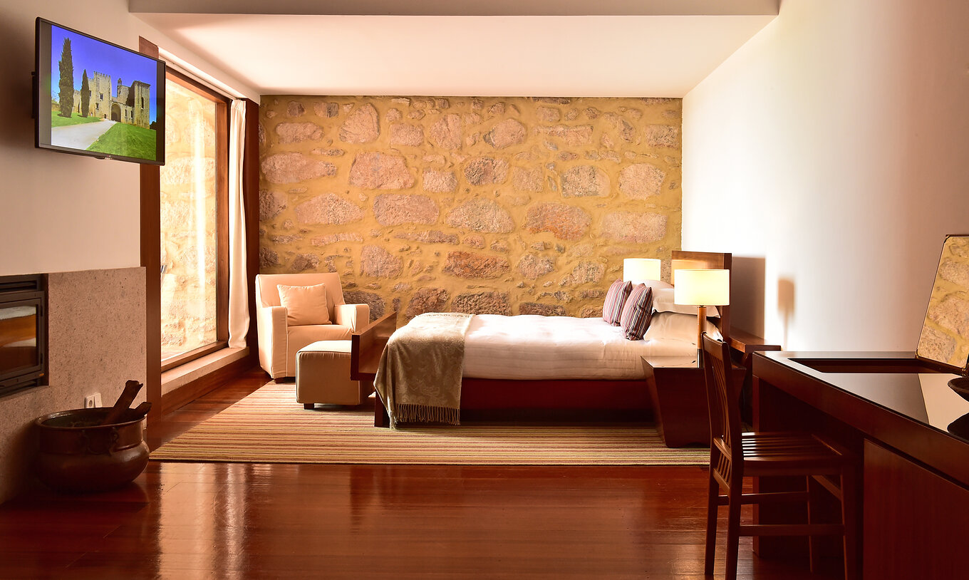 Die Standard Suite der Pousada Mosteiro Crato hat ein Doppelbett, einen Sessel, TV, einen Schreibtisch und Kamin