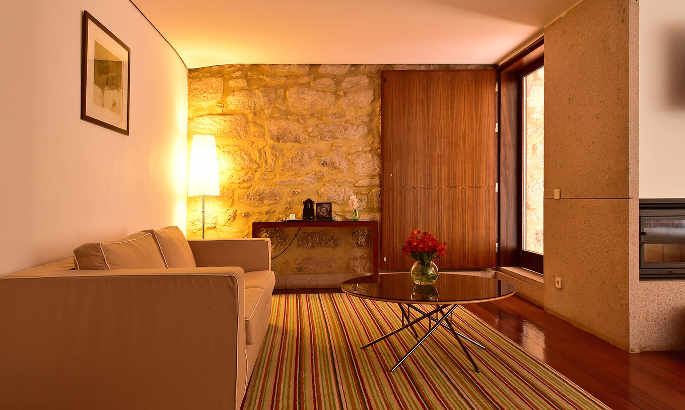 Die Standard Suite der Pousada Mosteiro Crato hat ein Doppelsofa mit einem kleinen Tisch und Blick auf den Balkon