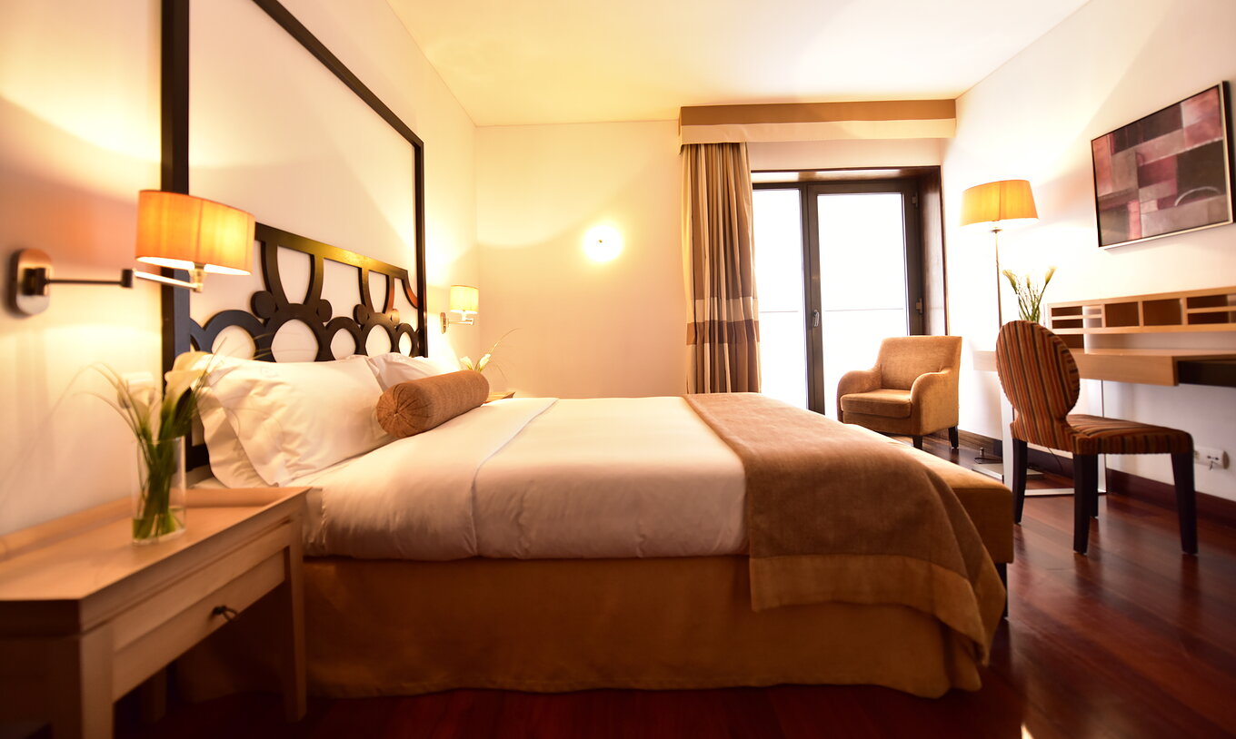 Die Standard Suite der Pousada Convento Tavira hat ein Doppelbett mit Nachttisch und einen Schreibtisch mit einem Stuhl