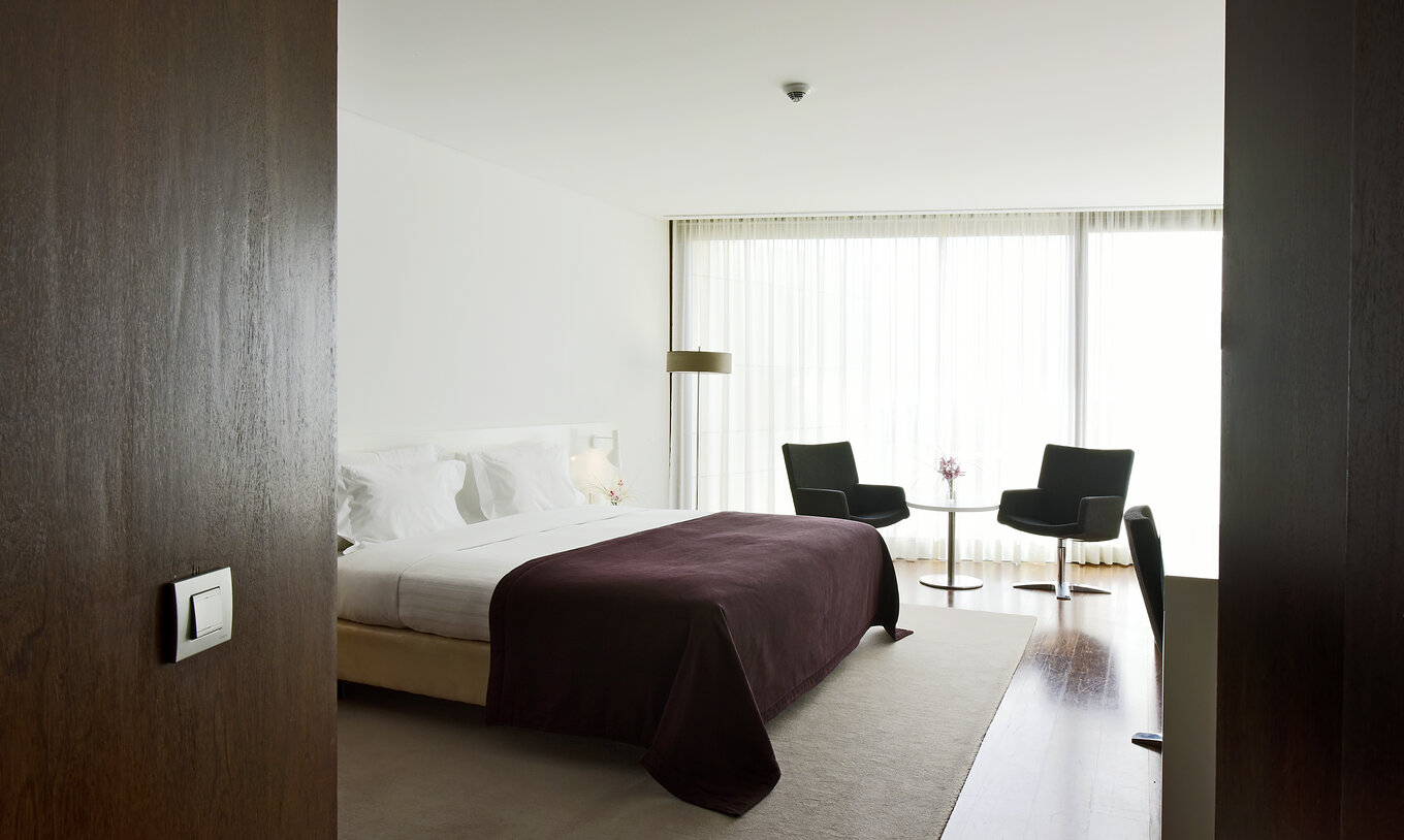 Das klassische Plus Zimmer der Pousada Palácio Estoi hat ein Doppelbett, ein Fenster, Teppich und einen Tisch mit Stühlen