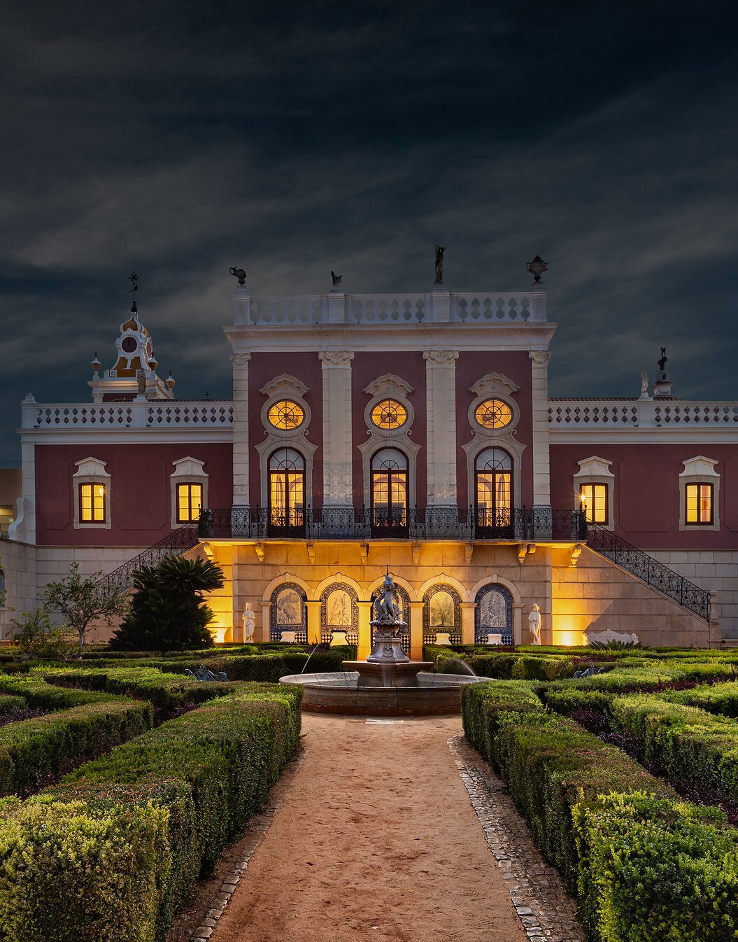 Nachtblick auf das historische Hotel in Faro, Pousada Palácio do Freixo, mit Gärten und einem beleuchteten Brunnen