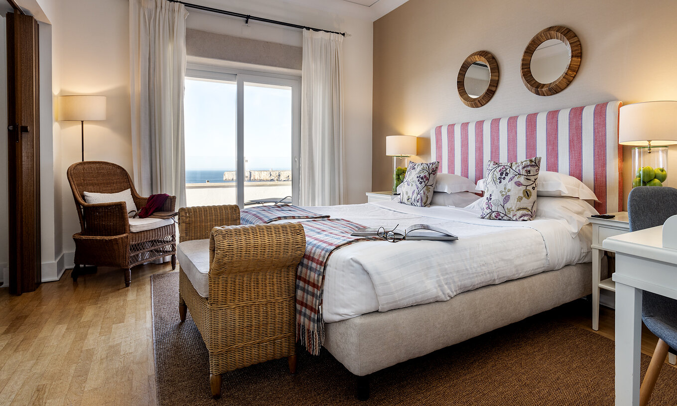 Die Master Suite der Pousada Sagres hat zwei Betten mit gestreiftem Kopfteil, zwei runde Spiegel und einen Balkon