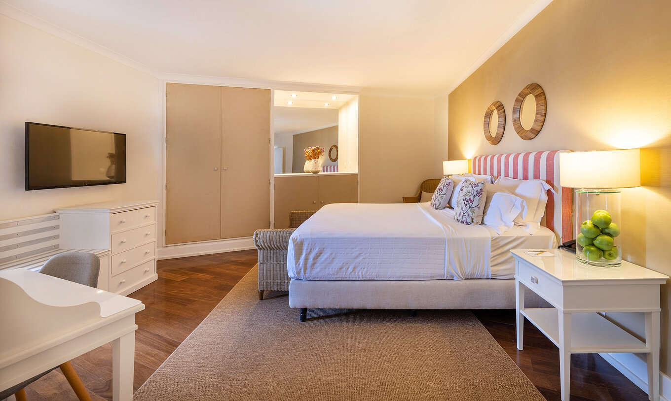 Die Special Suite der Pousada Sagres hat ein Schlafzimmer mit Doppelbett, Schränken, Spiegel, Schreibtisch und Fernseher