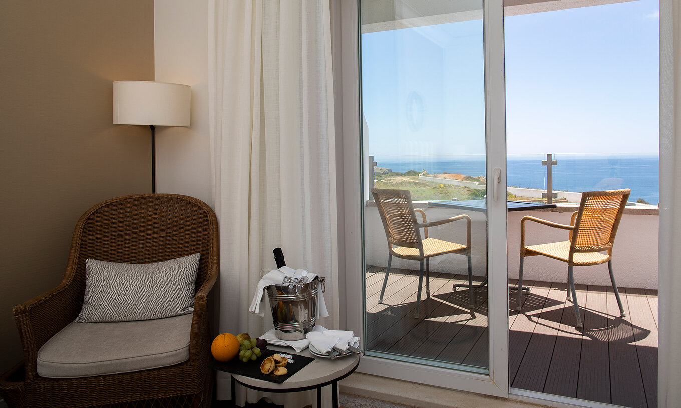 Das Superior Vista Mar Premium Zimmer der Pousada Sagres hat einen Balkon mit Tisch und Stühlen und einen Sessel