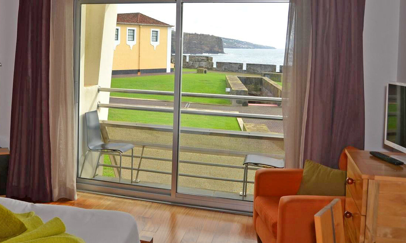Das Klassische Zimmer der Pousada Forte Angra do Heroísmo hat einen Balkon mit zwei Stühlen und Meerblick