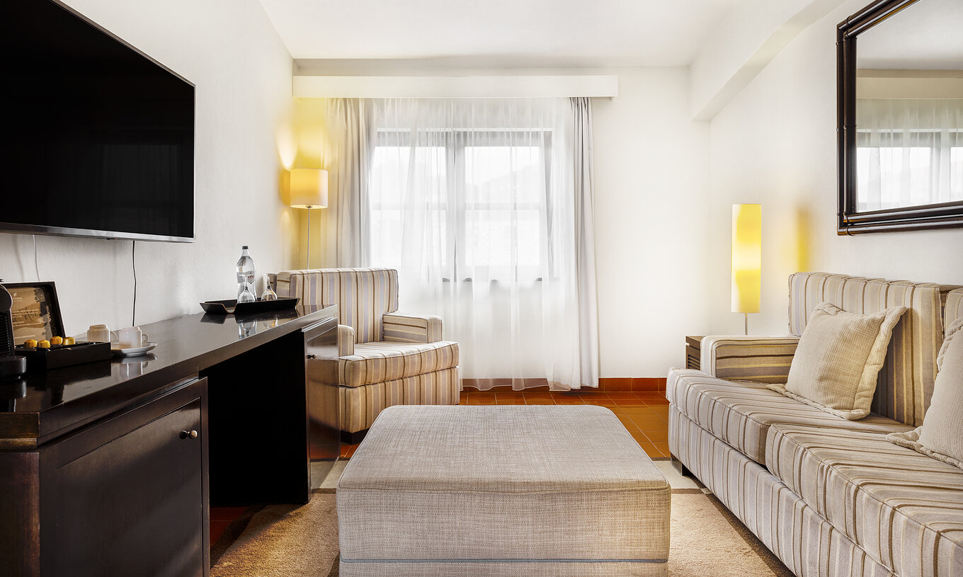 Die Master Suite der Pousada Forte Horta hat ein Doppelbett, einen Sessel, einen Fernseher und ein großes Fenster