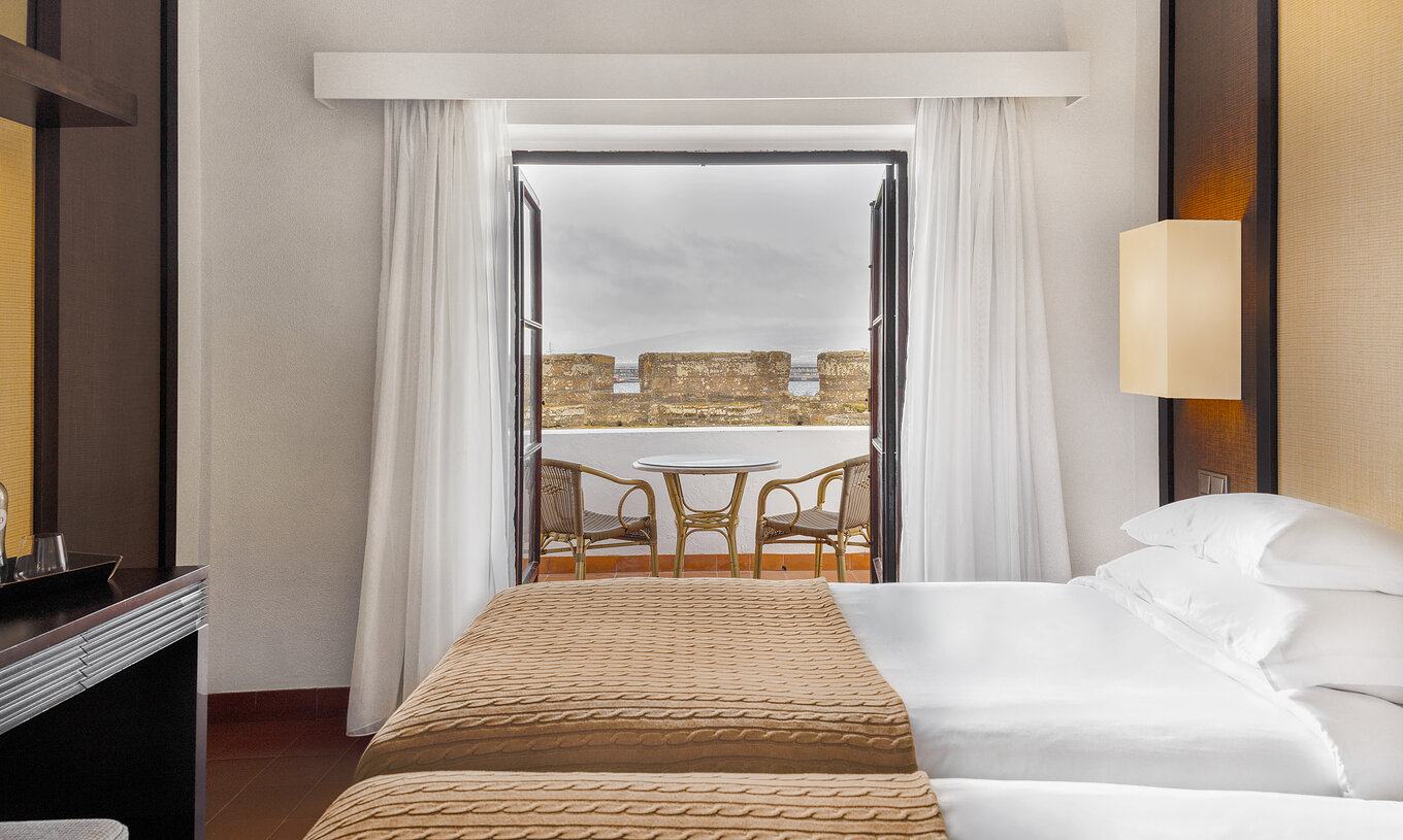 Das Superior Zimmer der Pousada Forte Horta hat einen Balkon mit Tisch und Stühlen sowie Blick auf das Fort