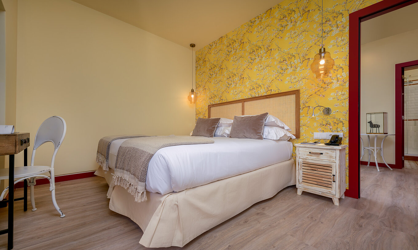 Die Suite der Casa Lidador - Óbidos hat ein Doppelbett, blühende Tapete und einen Nachttisch