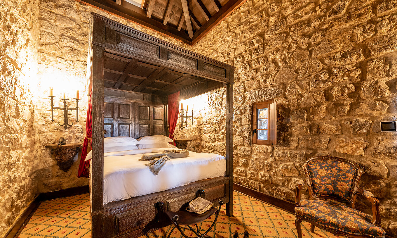 Die Spezial Suite der Pousada Castelo Óbidos hat ein Doppelbett mit Nachttisch im mittelalterlichen Stil