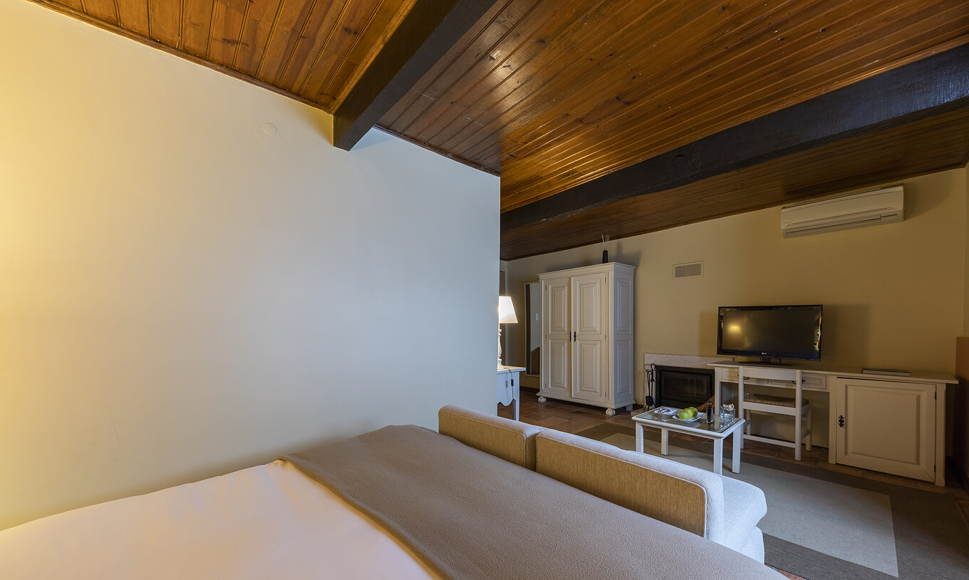 Das Standardzimmer Casa do Castelo der Pousada Castelo Óbidos hat einen Fernseher einen Schreibtisch und ein bequemes Sofa