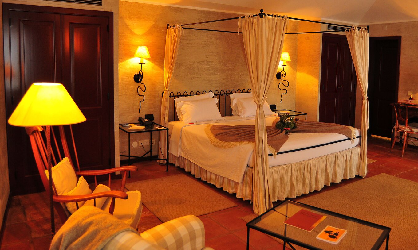 Das Double Deluxe Room der Pousada Convento Belmonte hat ein Doppelbett mit zwei Nachttischen und drei Lampen