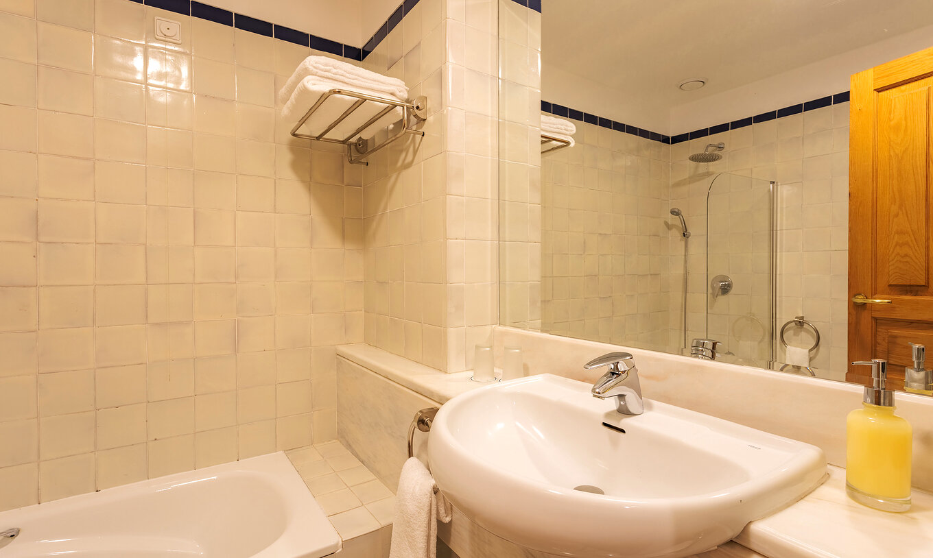 Das klassische Zimmer der Pousada Ourém hat ein Waschbecken mit großem Spiegel und eine Badewanne mit Dusche