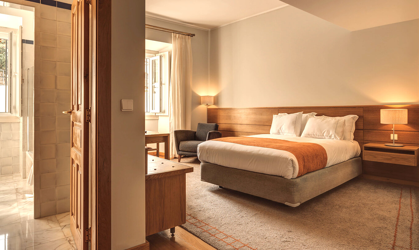 Das Familienzimmer der Pousada Ourém hat ein Doppelbett, ein Fenster und einen Nachttisch