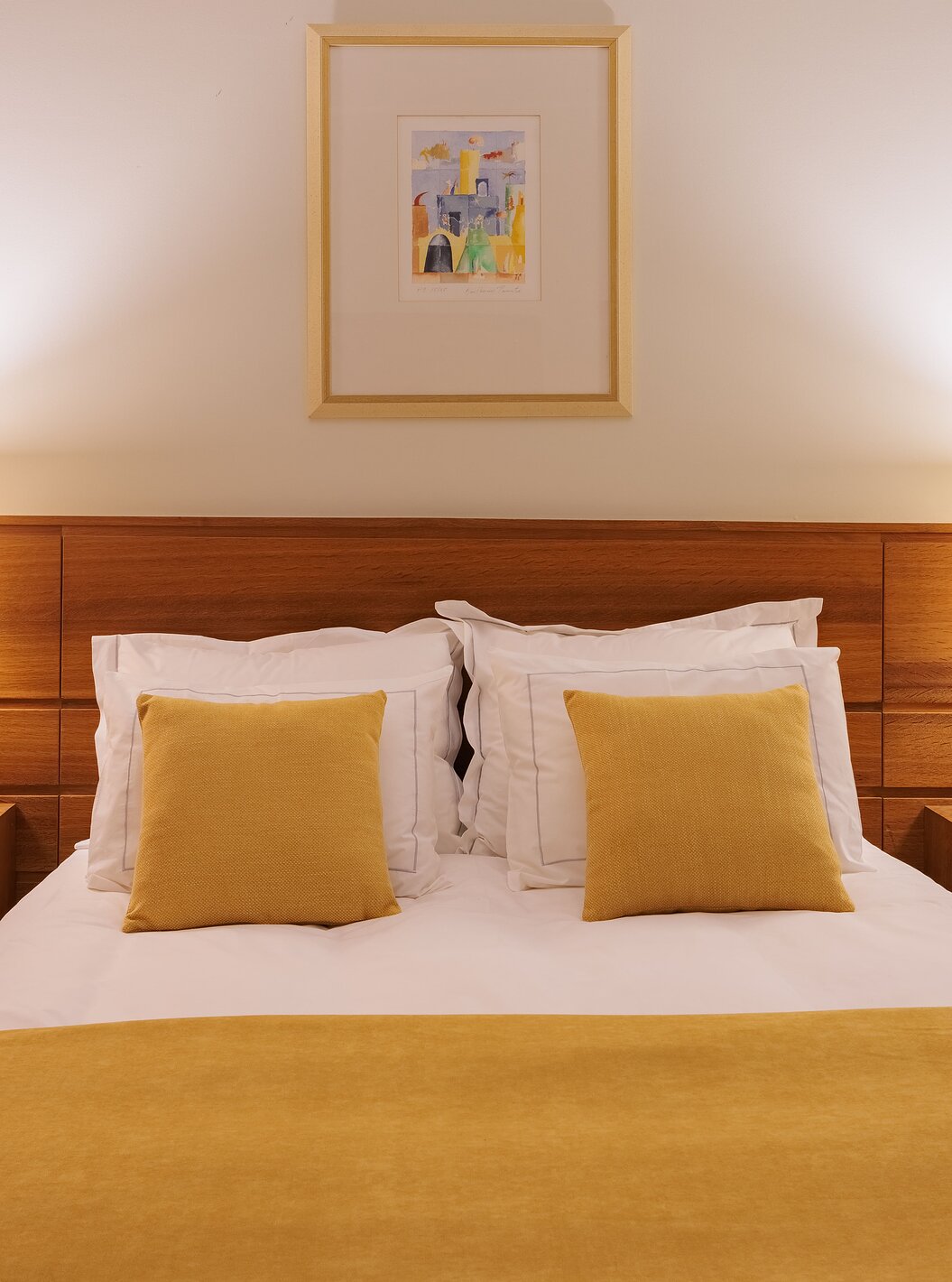 Das Einzelzimmer der Pousada Ourém hat ein Doppelbett mit zwei Nachttischen und einer gelben Bettdecke