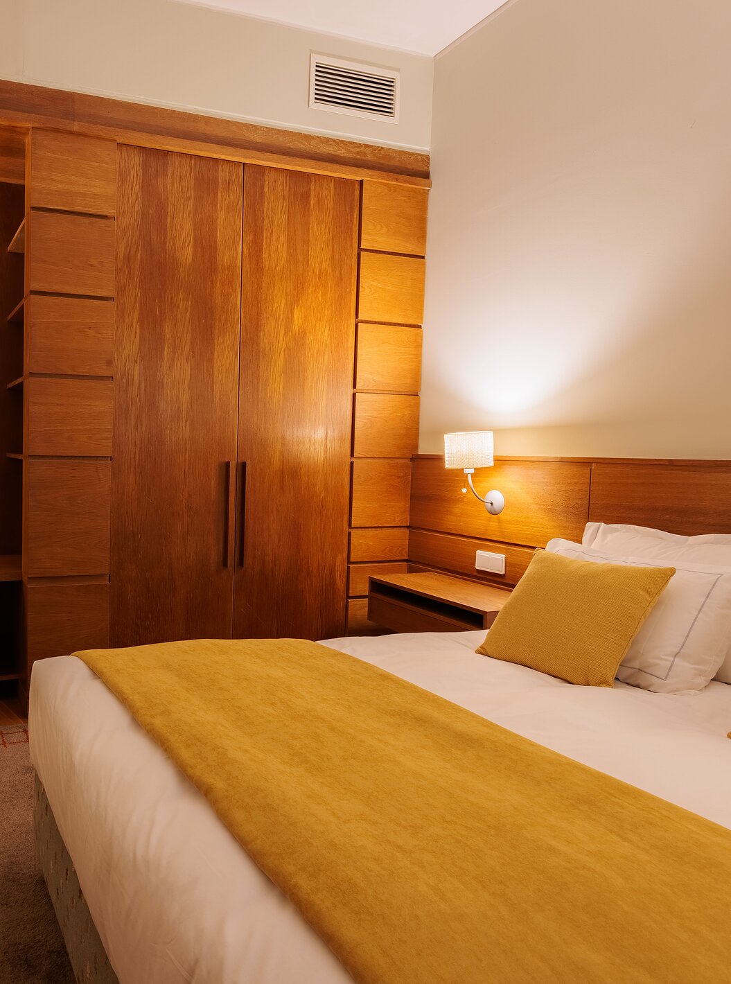 Das Einzelzimmer der Pousada Ourém hat ein Doppelbett mit gelber Bettdecke und einem Schrank daneben