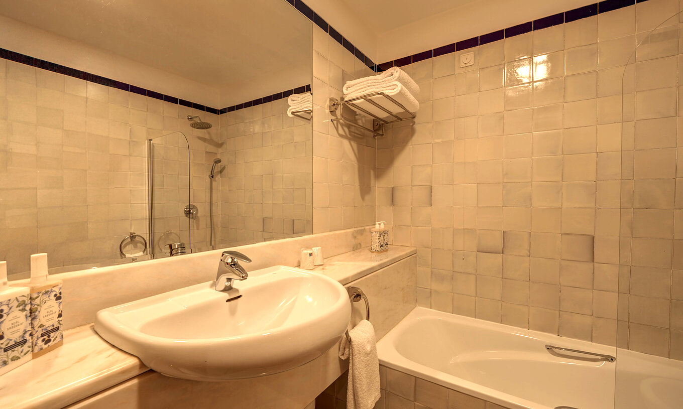 Das Superior Familienzimmer der Pousada Ourém hat ein Bad mit Waschbecken, großem Spiegel und Badewanne