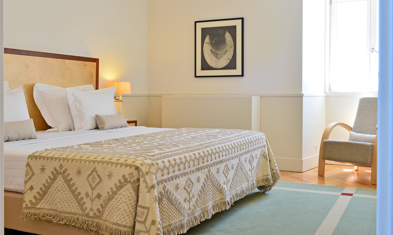 Die Large Family der Pousada Serra da Estrela hat ein Schlafzimmer mit Doppelbett, einen Sessel und ein Bild an der Wand