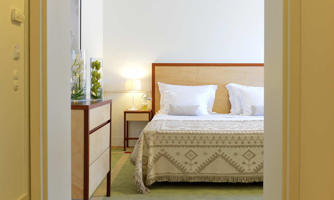 Das Superior Family der Pousada Serra da Estrela hat ein Doppelbett mit Holz-Kopfteil und ein Möbelstück aus Holz