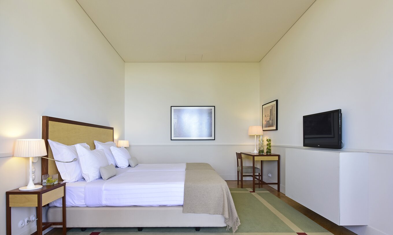 Das Superior Zimmer der Pousada Serra da Estrela hat zwei Betten und zwei Nachttische, einen Schreibtisch und einen Fernseher