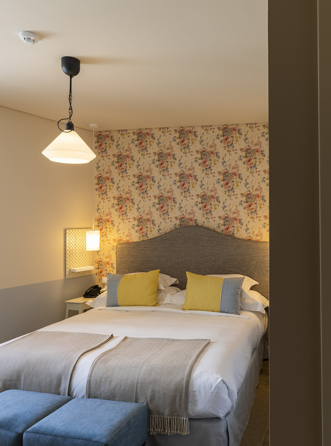 Das Classic Room der Pousada Vila Óbidos hat ein Doppelbett, florale Tapete und ein Bad mit Dusche und Toilette