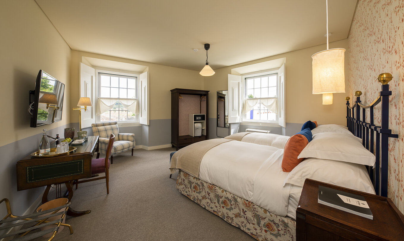 Das Premium Room der Pousada Vila Óbidos hat zwei Betten, einen Schrank mit Safe, zwei Fenster und einen Fernseher