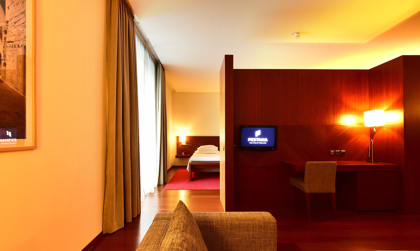 Die Standard Suite der Pousada Viseu hat ein Sofa, einen Schreibtisch mit Lampe und Stuhl sowie einen Fernseher