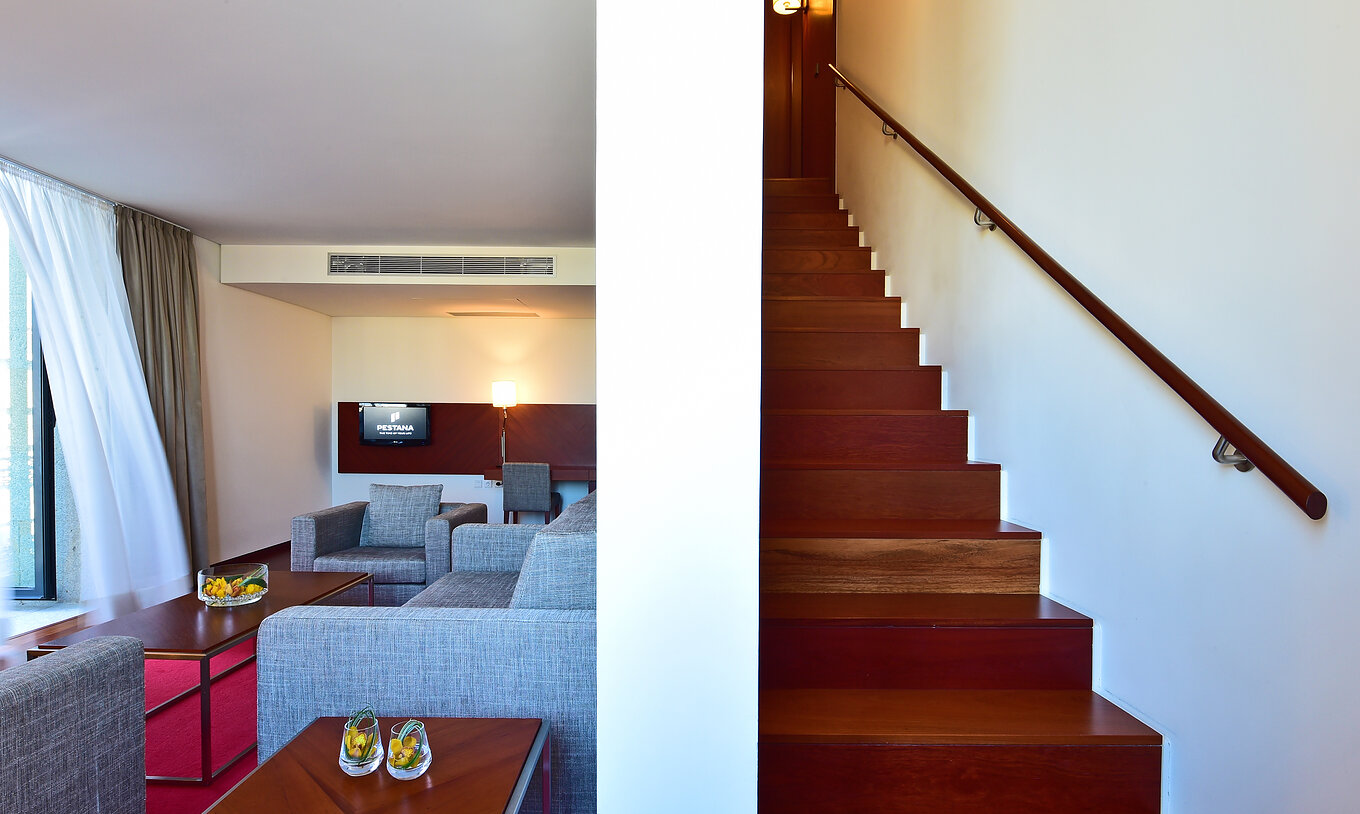 Die Mezzanine Suite der Pousada Viseu hat zwei Sessel, ein Sofa, einen Schreibtisch, Fernseher und Treppe zur Mezzanine