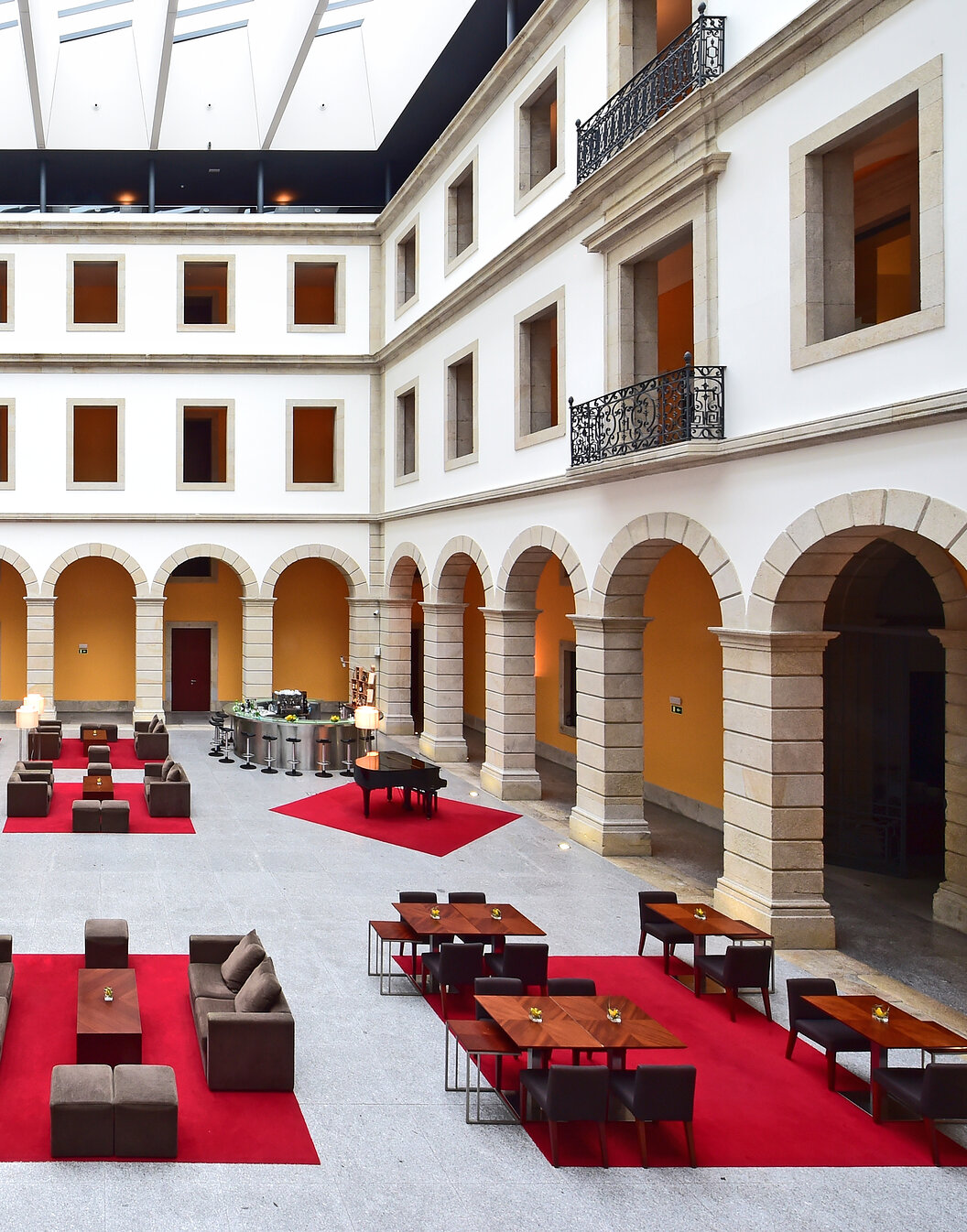 Innenhof der Pousada Viseu, Historisches Hotel in Viseu, mit Bögen und mehreren Sofas, Bänken und Bar im Hintergrund