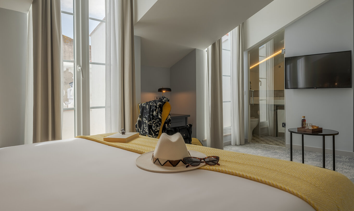 Die Junior Suite der Pousada Alfama hat zwei große Fenster, einen Fernseher und ein Badezimmer mit transparenter Tür